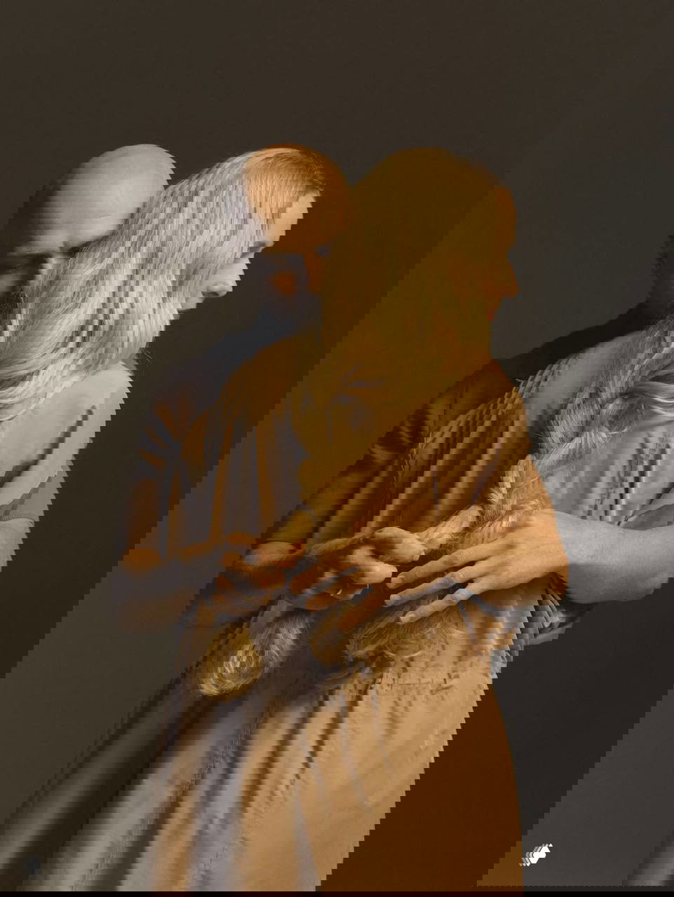 Эмоциональный студийный кадр: пара в объятиях друг друга, художественная композиция и тёплая цветовая палитра для журнальной съёмки.