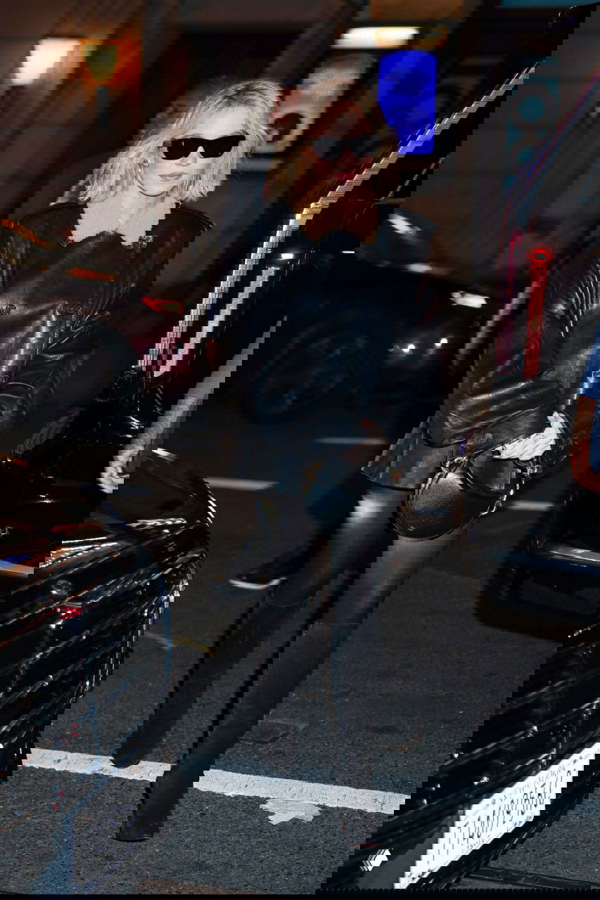 Тёмный кожаный жакет с меховой оторочкой, чёрные колготки и высокие сапоги в ночном выходе — акцент на верхней одежде.