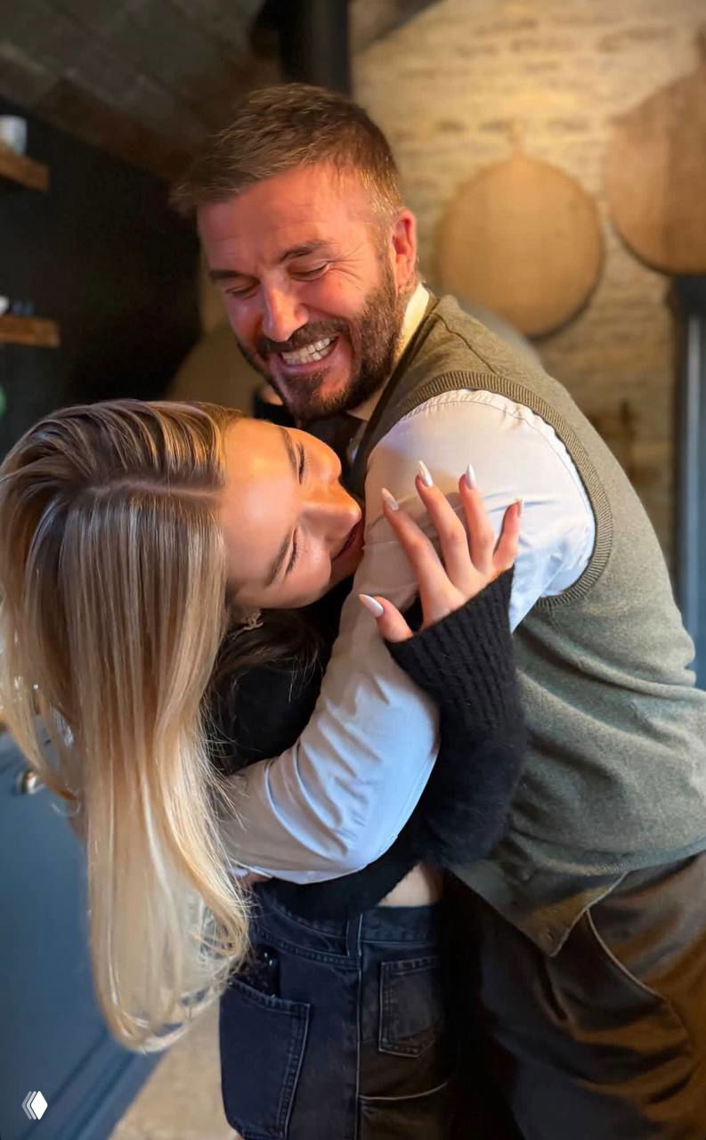 Мужчина с бородой смеётся и обнимает молодую женщину в тёплой позе, кадр передаёт семейное тепло и радость праздничного вечера.