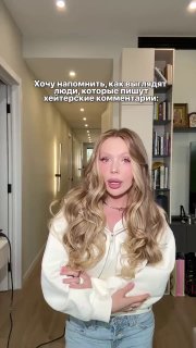 Крупный план: Карина Кросс жестами акцентирует внимание, на экране виден субтитрованный текст о хейтерских комментариях — фрагмент ролика блогерши.