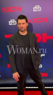 Сергей Гилев позирует на красной дорожке на фоне бренд-волла с логотипами; портретный кадр с водяным знаком Woman.ru