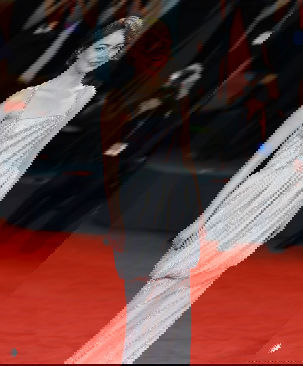 Полноформатный снимок на красной дорожке — актриса в светлом платье позирует перед фотокамерами на премьере или фестивале.