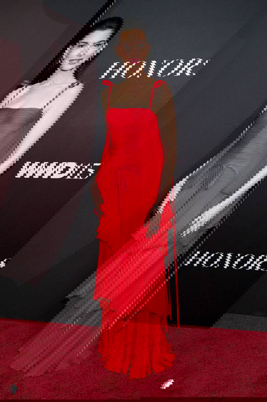 Энн Хэтэуэй в многослойном красном платье с рюшами и тонкими бретелями на фотоколле; женственный классический лук в насыщенном цвете.