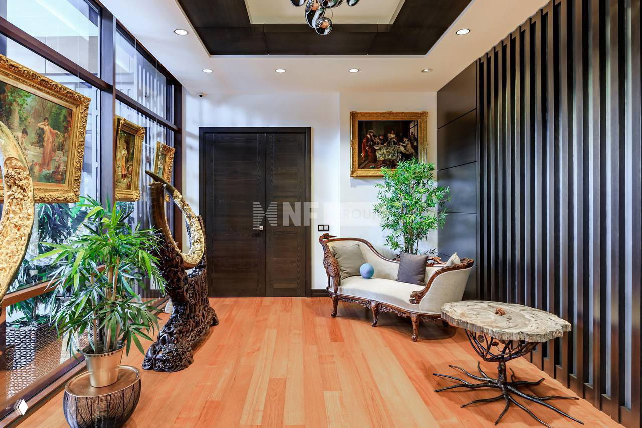 Коридор или холл с деревянным полом, резной мебелью и картинами в позолоченных рамах — элементы интерьера, подчёркивающие антикварный стиль дома.