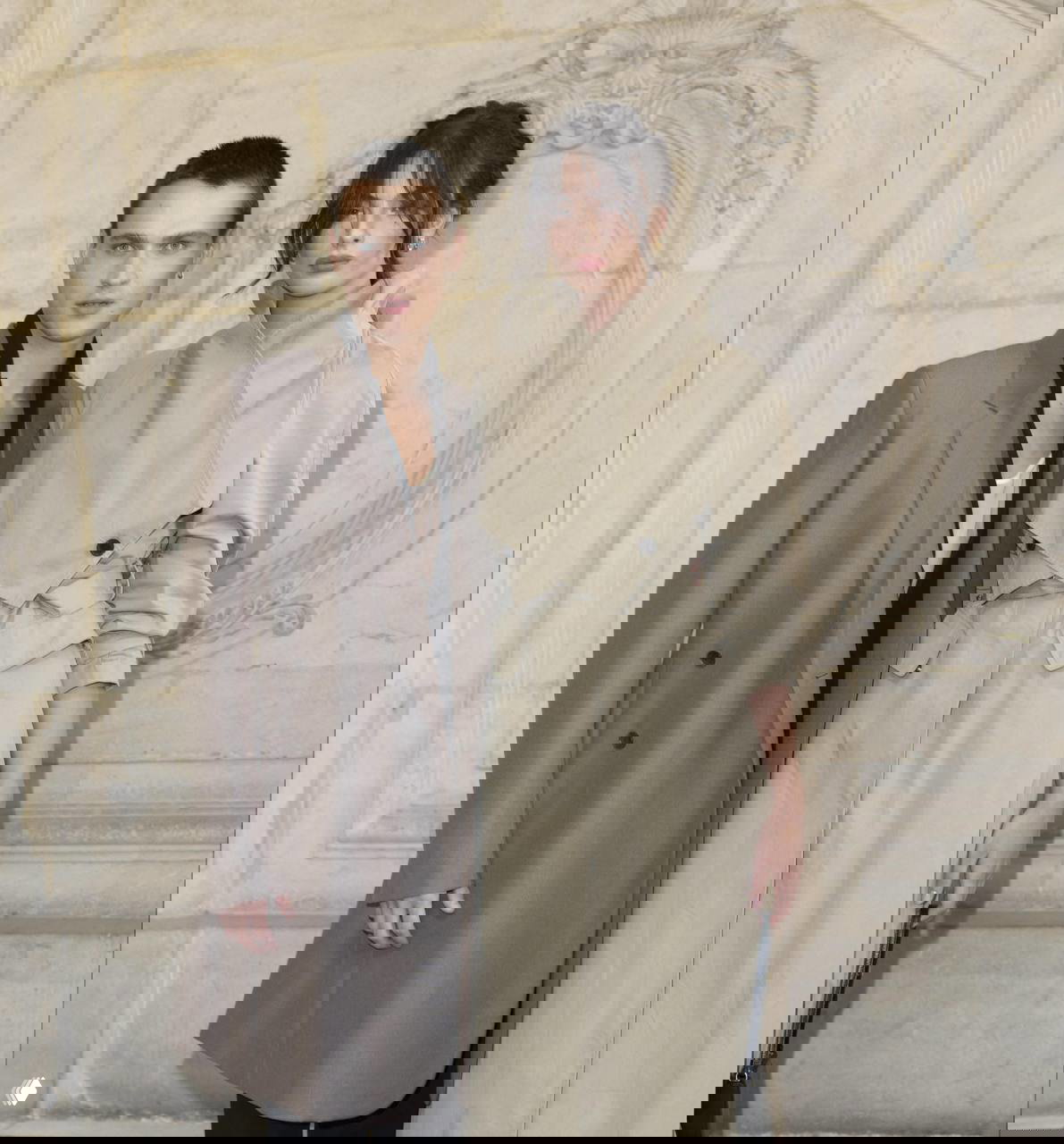 Фотоколл: Дева Кассель и Сол Нанни в пальто и тренчах на фоне классической архитектуры, образ строгий и стилизованный.