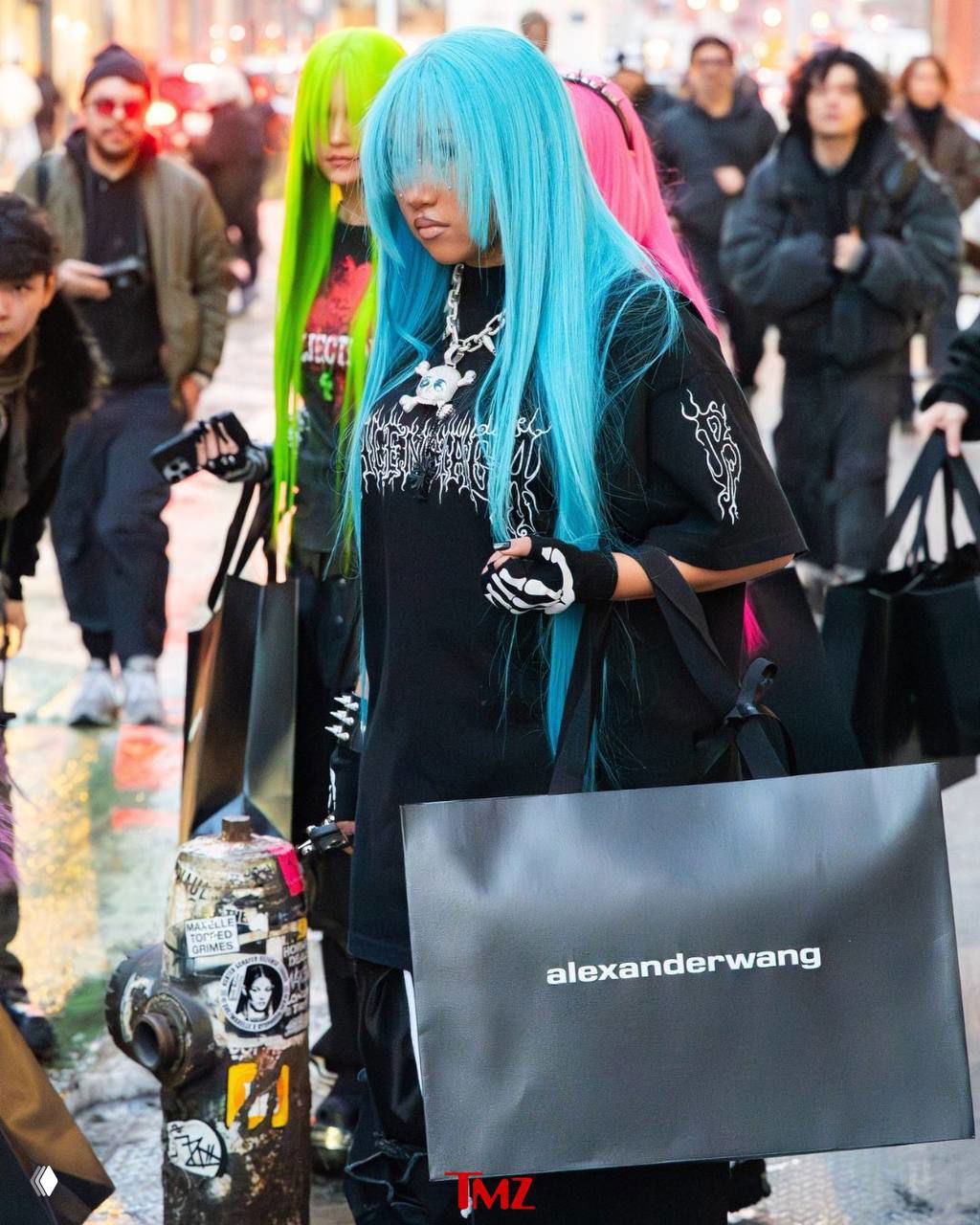 Группа молодых людей с разноцветными париками идёт по тротуару Нью‑Йорка; на переднем плане девушка в бирюзовом парике.