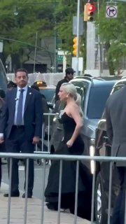 Певица выходит из автомобиля в чёрном платье у кортежа на тротуаре, рядом люди, охрана и кадр репортажа.