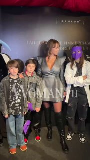 Полина Диброва в серебристом платье, Дмитрий Дибров и дети на красной дорожке премьеры «Щелкунчик» на фоне баннера иммерсивного театра.