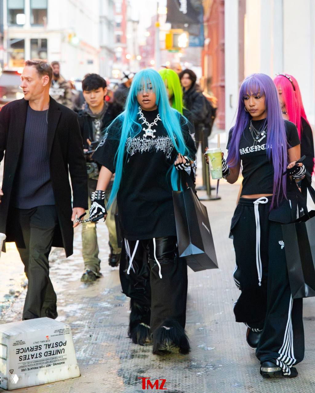 Девушка в бирюзовом парике идёт по улице Нью‑Йорка вместе с подругами в разноцветных париках, все с пакетами для шопинга.