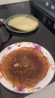 Процесс жарки и подача тонкого блина на сковороде и тарелке; видна бытовая кухонная поверхность и готовое тесто.