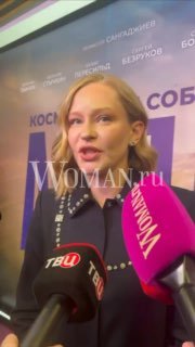 Юлия Пересильд даёт интервью на премьере у баннера мероприятия; в кадре видно несколько микрофонов с логотипами телеканалов и Woman.ru