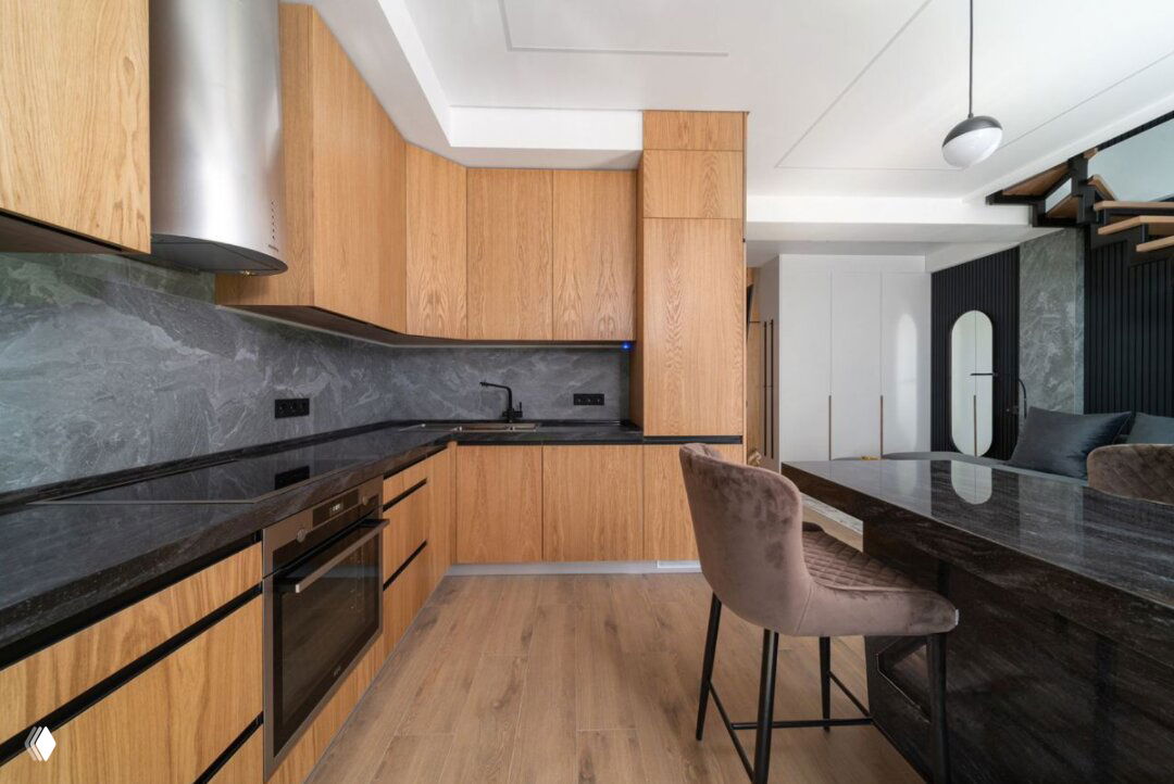 Кухня-столовая в современной отделке: деревянные фасады, тёмная столешница и обеденная зона в едином стиле с напольным покрытием.