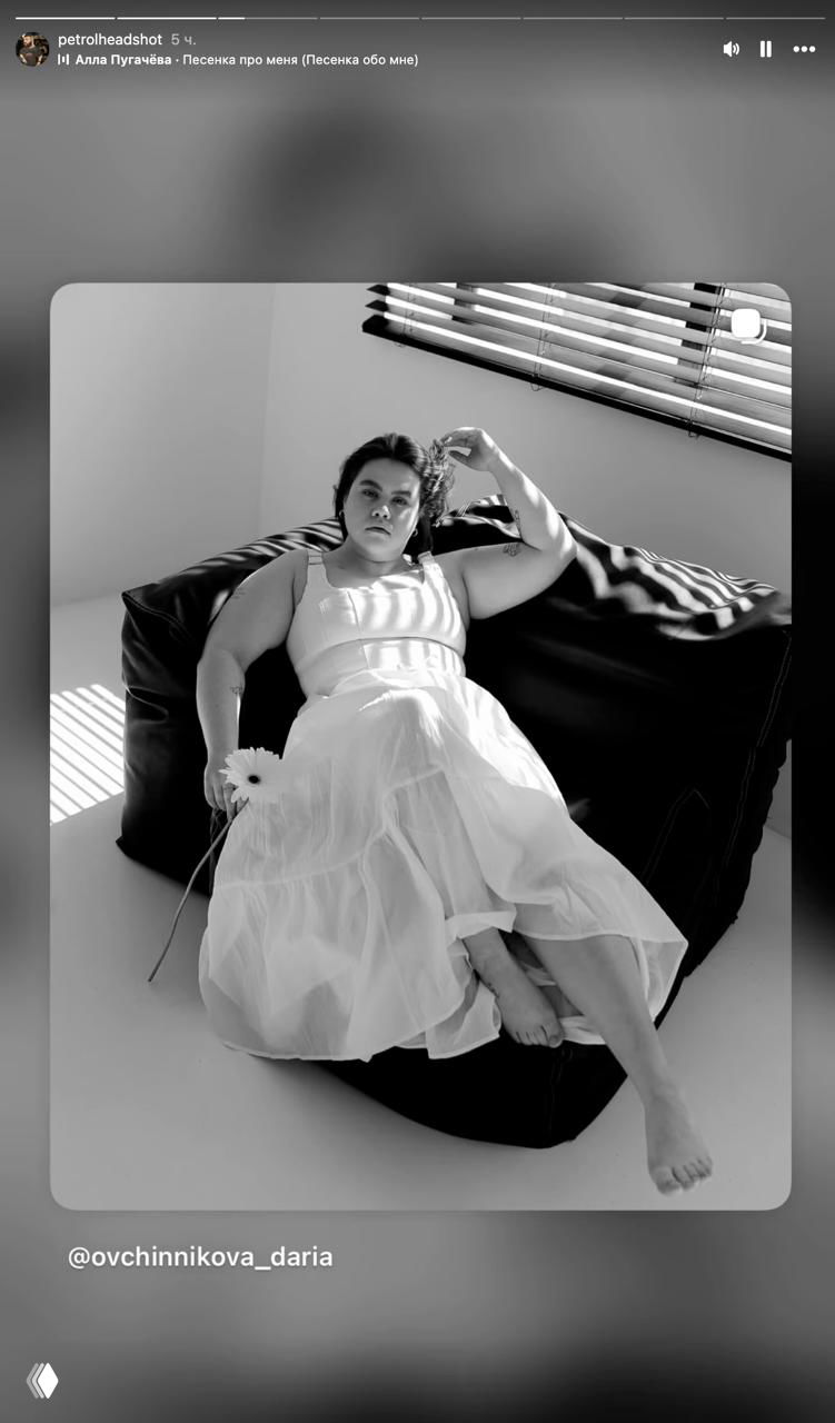 Чёрно‑белая фотография женщины в платье, лежащей на кресле в артистичной позе — кадр репоста из сторис, указан автор.
