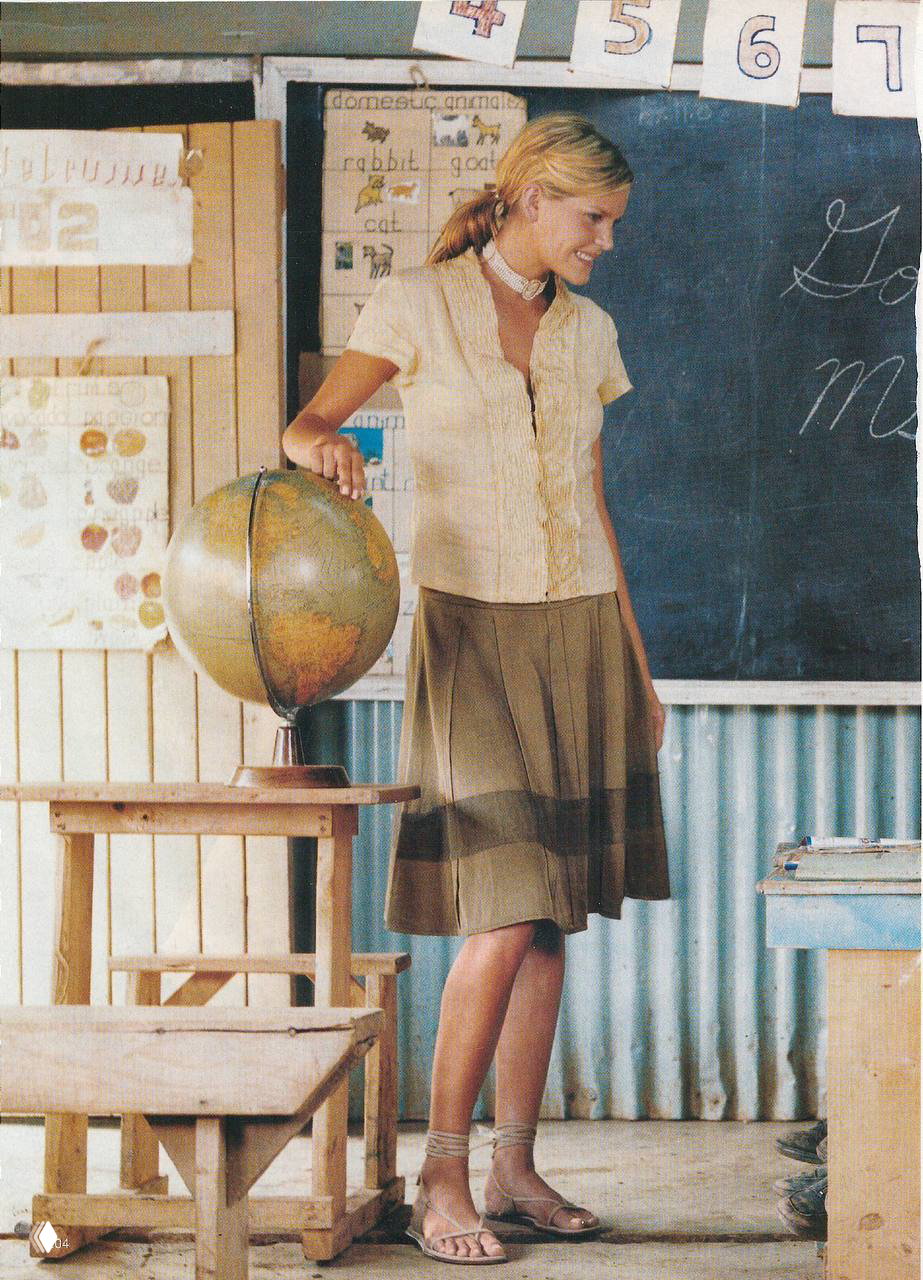 Сцена в школьном классе: модель возле глобуса и школьной доски, винтажные парты и реквизит создают атмосферу учебного интерьера.