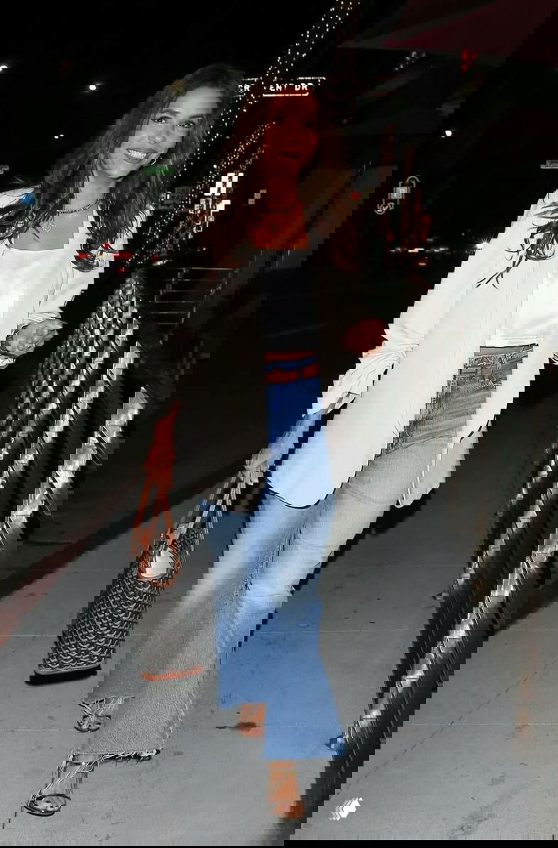 Лорен Санчес идёт по улице в светлом пиджаке, сатиновом топе и широких джинсах, улыбается и несёт большую сумку — кадр ночной прогулки по ЛА.