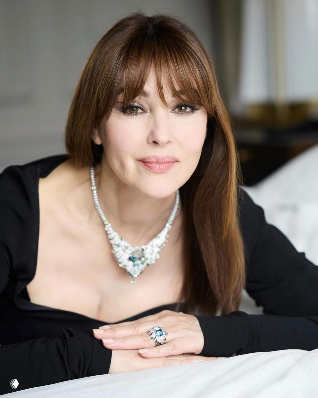 Портрет Моники Беллуччи крупным планом: естественный макияж, аккуратная причёска и эффектное ожерелье Cartier на светлом фоне.