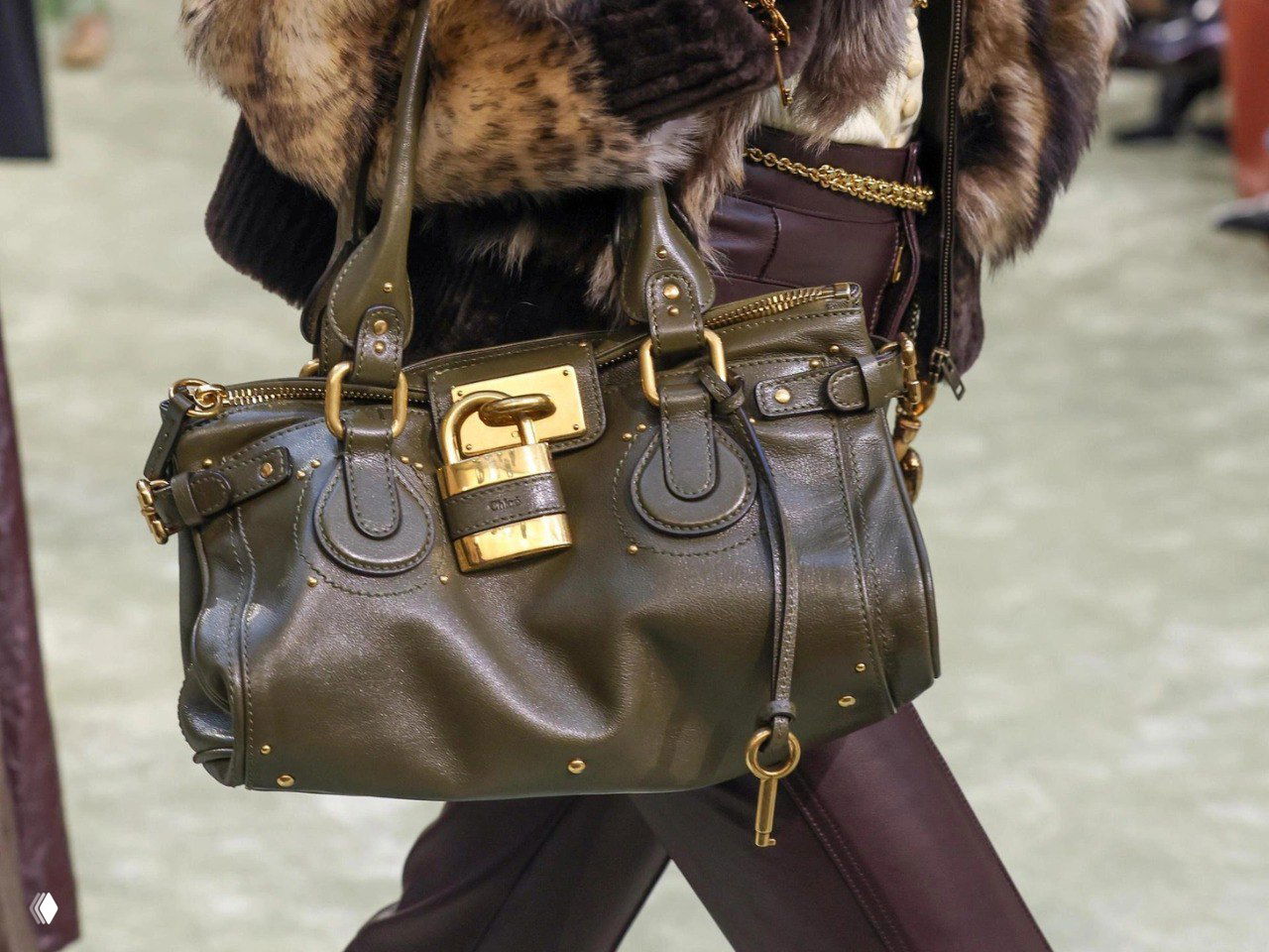 Крупный план оливково-зелёной сумки Chloé Paddington с массивной золотой застёжкой и характерной формой, акцент на фурнитуру