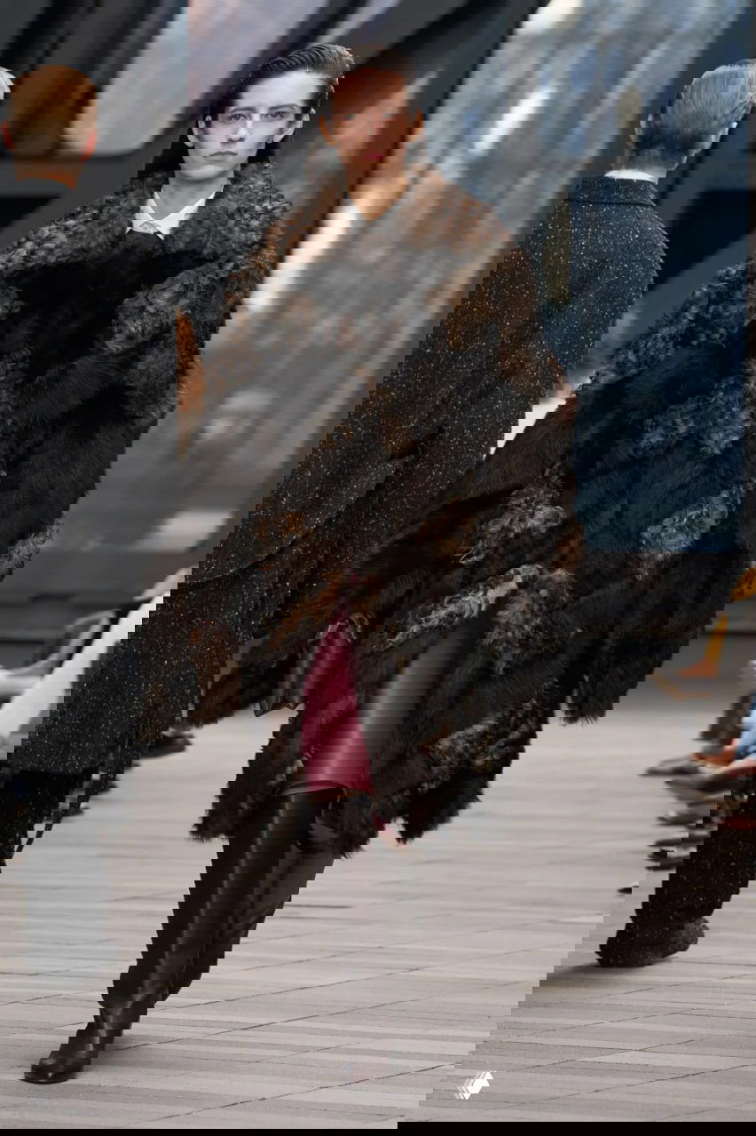 Объёмная тёмная шуба с рваной фактурой и высокая сапожная часть образа; драматичный аксессуар в спокойной коллекции Calvin Klein.