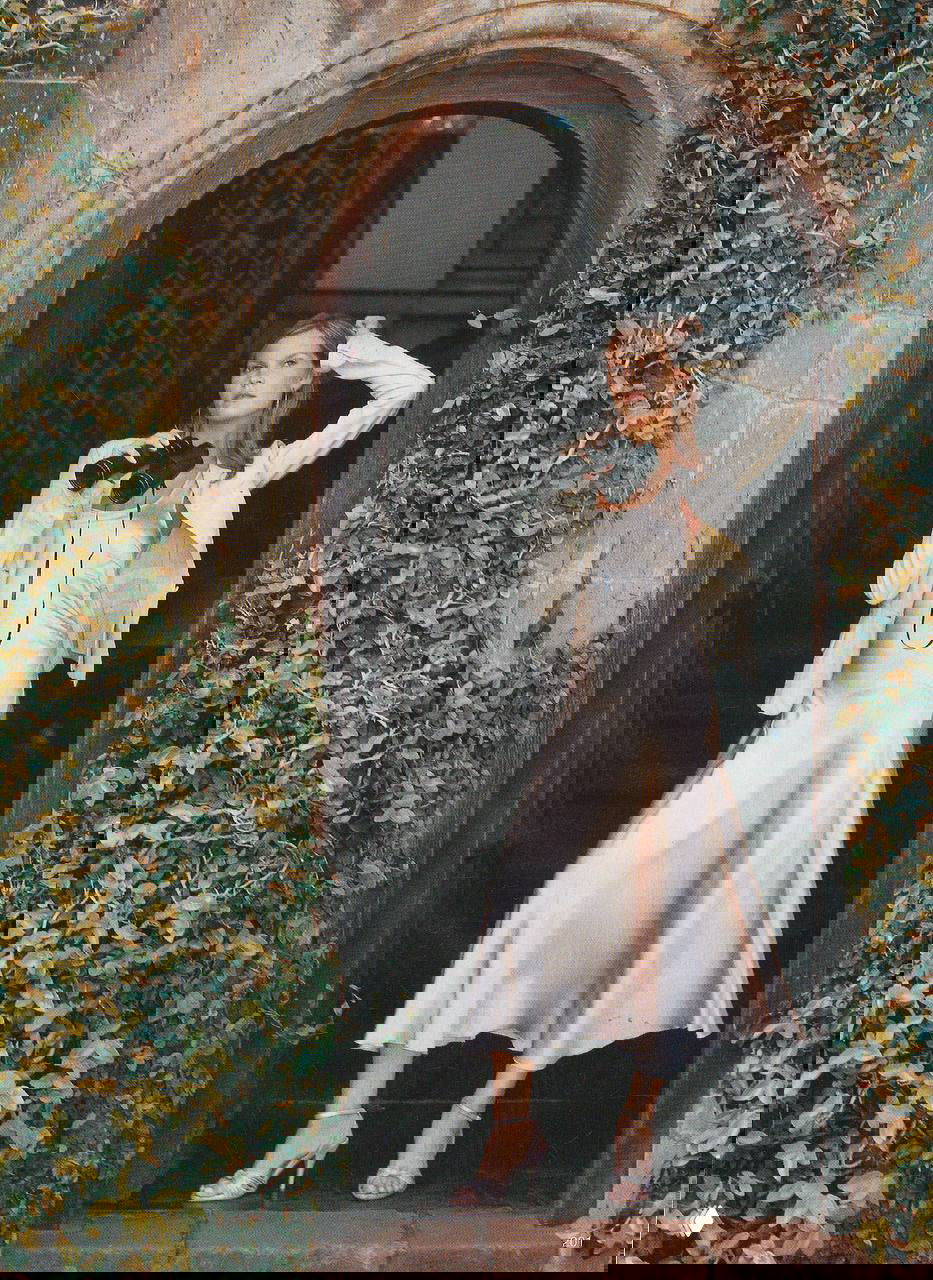 Портрет модели в арочном проёме в платье-комбинации с биноклем: элегантный завершающий кадр фотосессии для журнала, архитектурный фон.