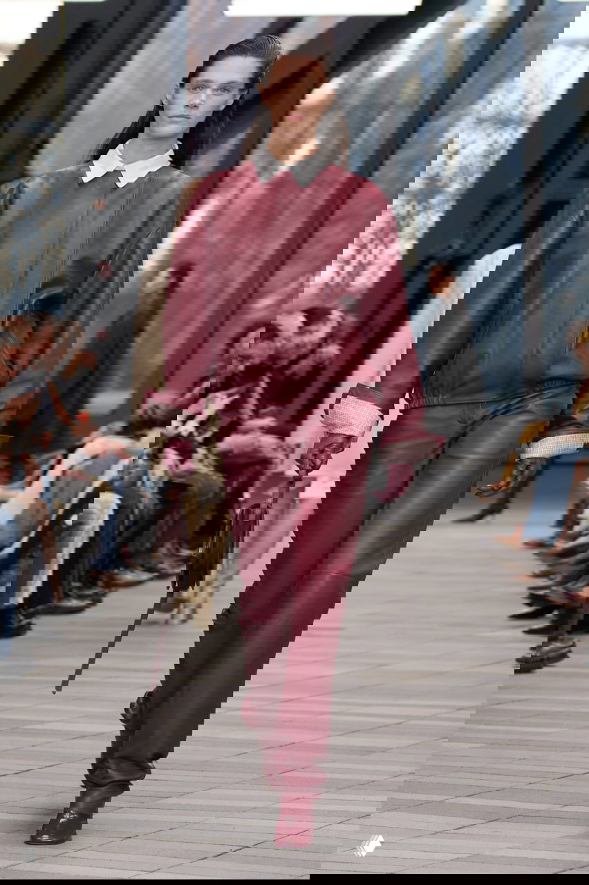 Модель в бордовом кожаном аутфите — куртка и брюки одного тона на подиуме Calvin Klein; строгие линии и минималистичный крой.