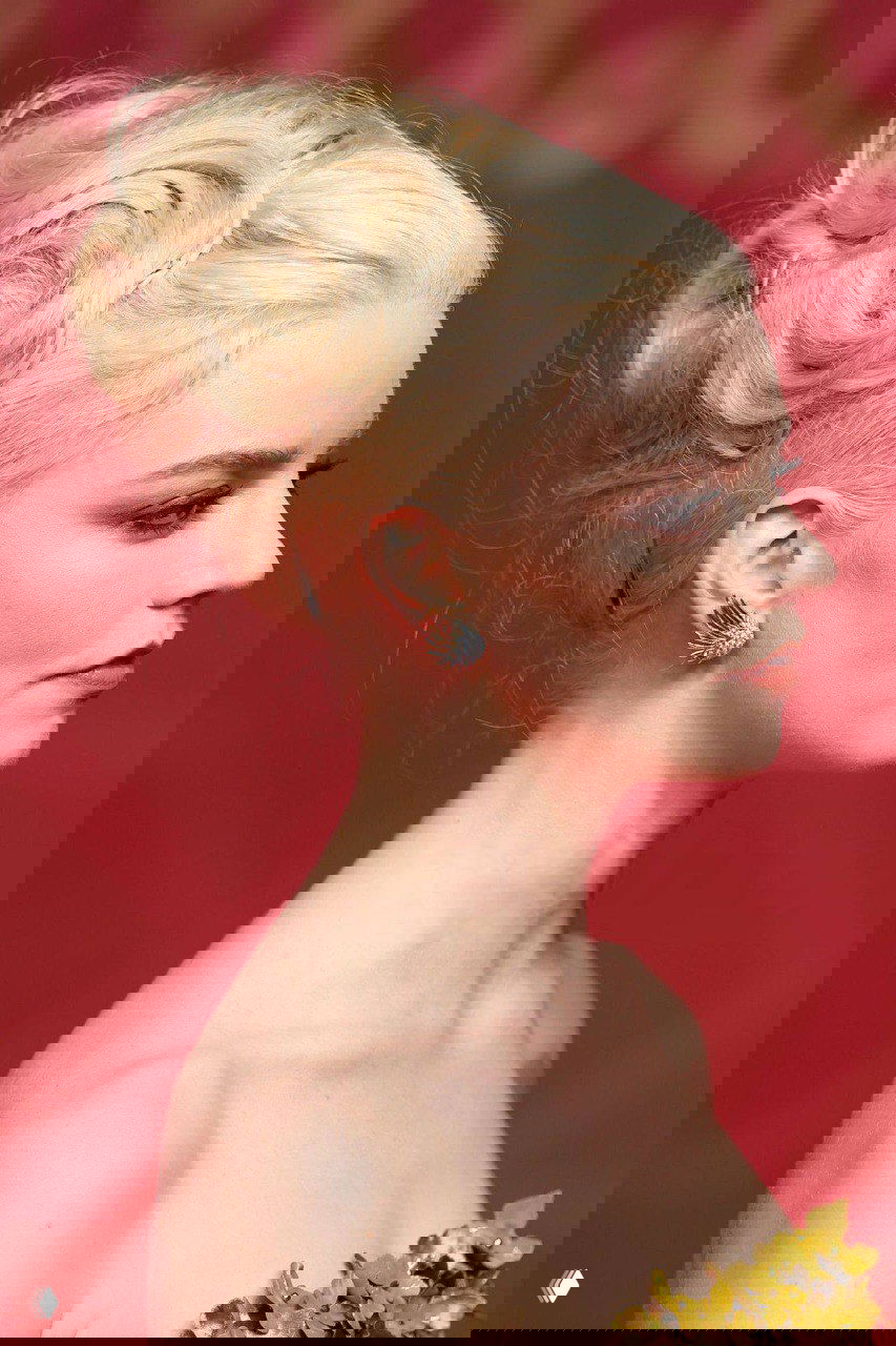 Профильный портрет с фокусом на укладке: завитые узоры на светлых волосах, похожие на розы, подчёркивают линию шеи и уха.