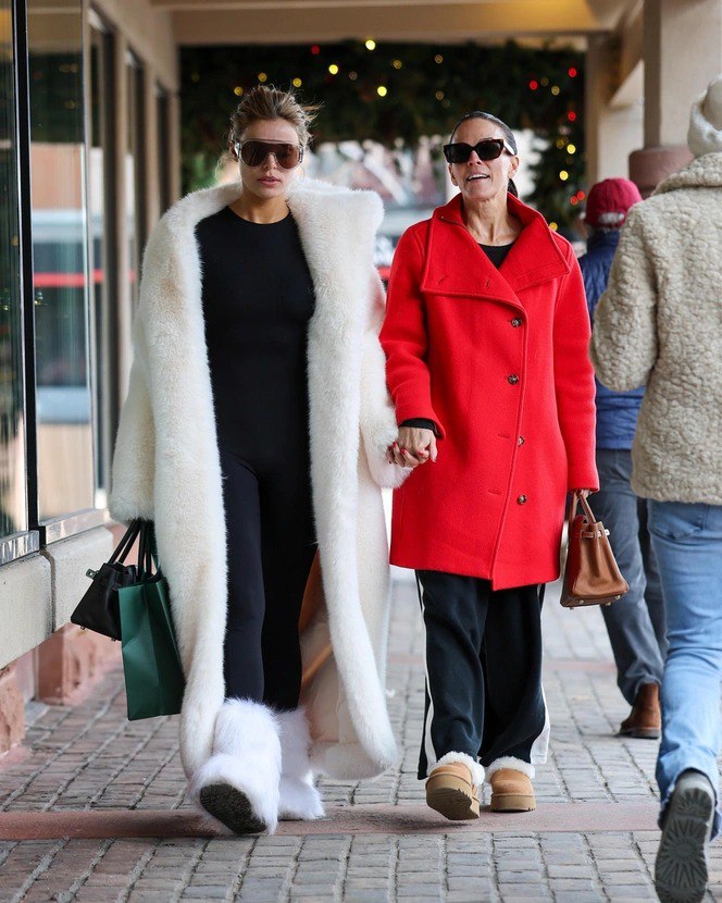 Длинная объёмная белая шуба на фоне улицы: чёрный комбинезон, просторная шуба и белые унты создают контраст с минималистичным total black луком.