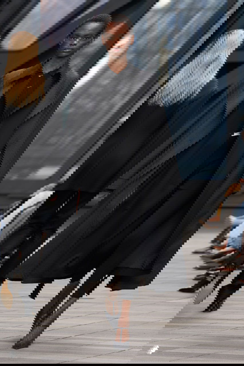 Чёрный длинный плащ и строгий костюмный силуэт на модели — минимализм в монохроме в коллекции Calvin Klein от Вероники Леони.