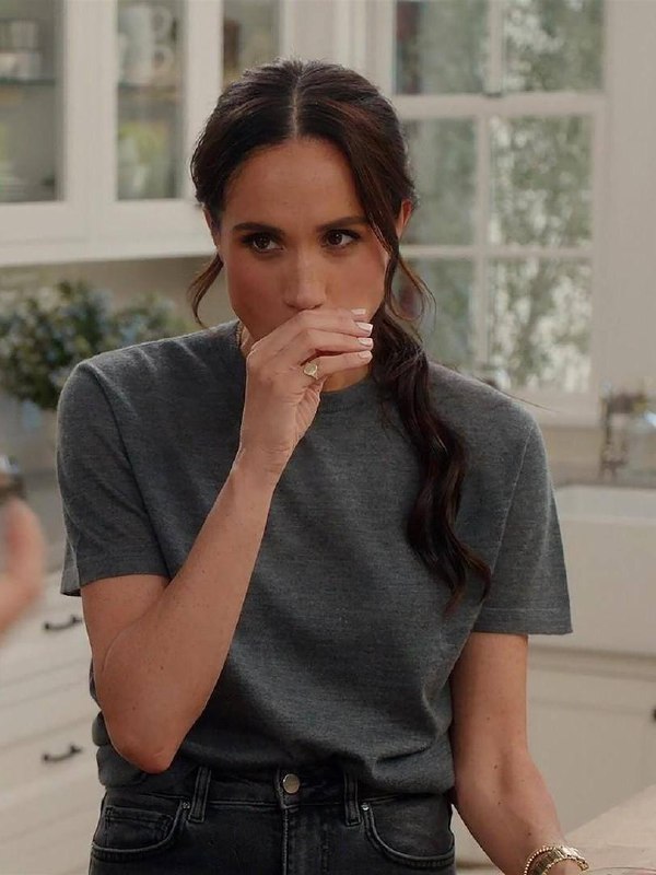 Женщина в серой футболке в кухонной обстановке, крупный план руки и украшений; натуральный образ и домашняя сцена.