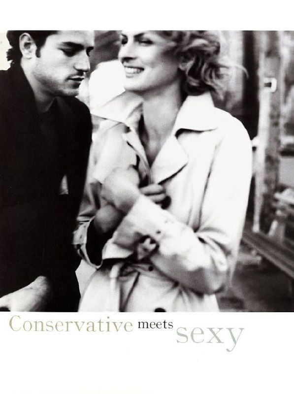 Чёрно‑белый кадр пары: мужчина и женщина в плаще и пиджаке улыбаются на фоне городской улицы, романтический винтажный портрет 1997 года.