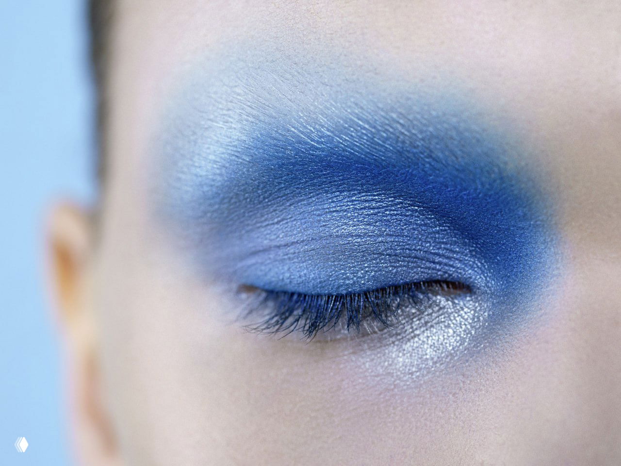 Макро закрытого глаза с насыщенным синим и перламутровым шиммером: детальная текстура теней и растушевка вблизи, редакционный beauty-кадр.