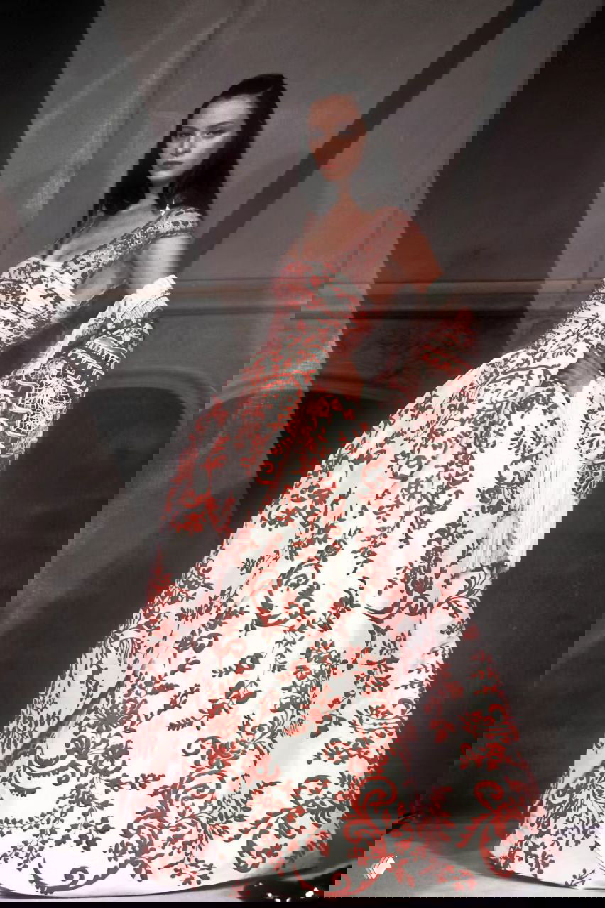 Модель в белом платье с крупным красным растительным узором и кружевной накидкой; принтованное кутюрное платье на подиуме Valentino, 1998.