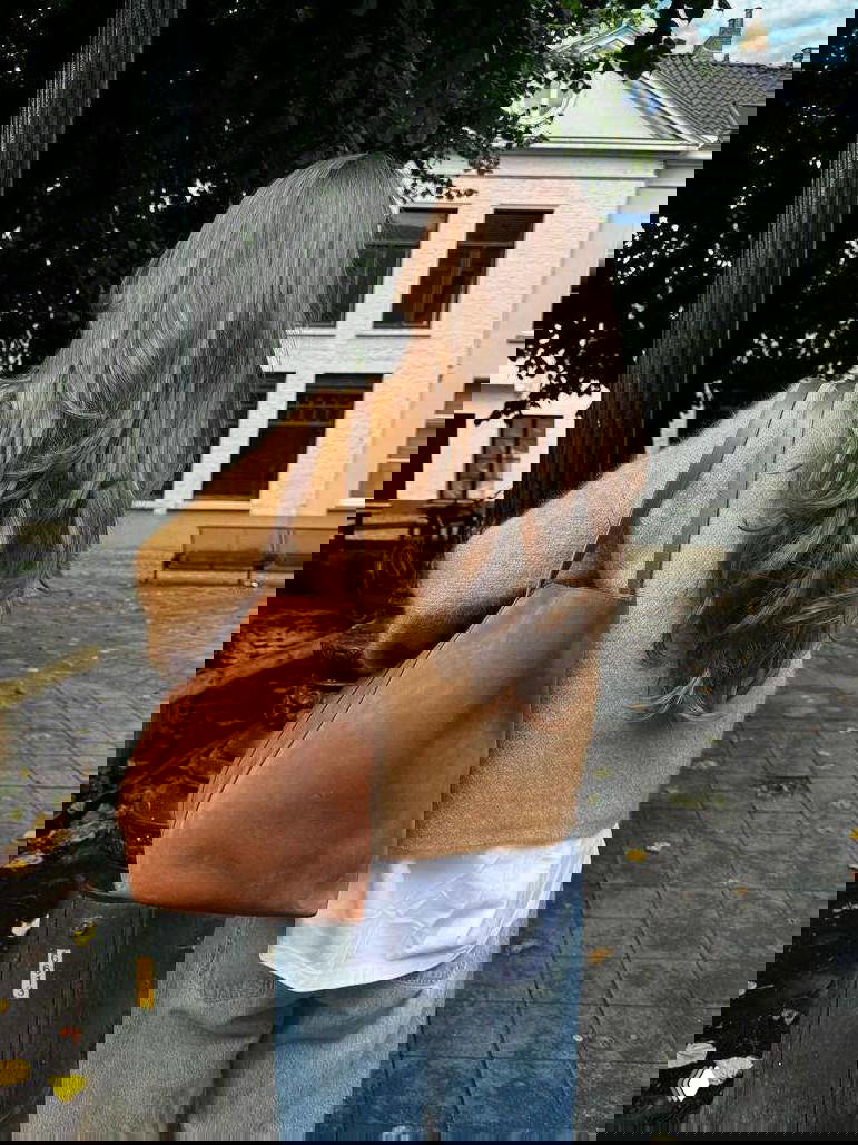 Женщина с удлинёнными слоями и мягкими локонами на фоне городской застройки — пример лёгкой укладки без фена.