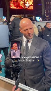 Вертикальный кадр: мужчина в костюме демонстрирует яркие эмоции на фоне толпы и экранов во время кинопремьеры.