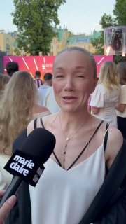 Дарья Мороз даёт блиц-интервью на Marie Claire Blogger Party: микрофон с логотипом, люди и сцена на заднем плане.