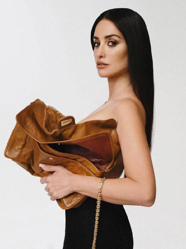 Пенелопа Крус в профиль с большой кожаной сумкой в руках — элегантный минимализм и акцент на аксессуарах для журнала.
