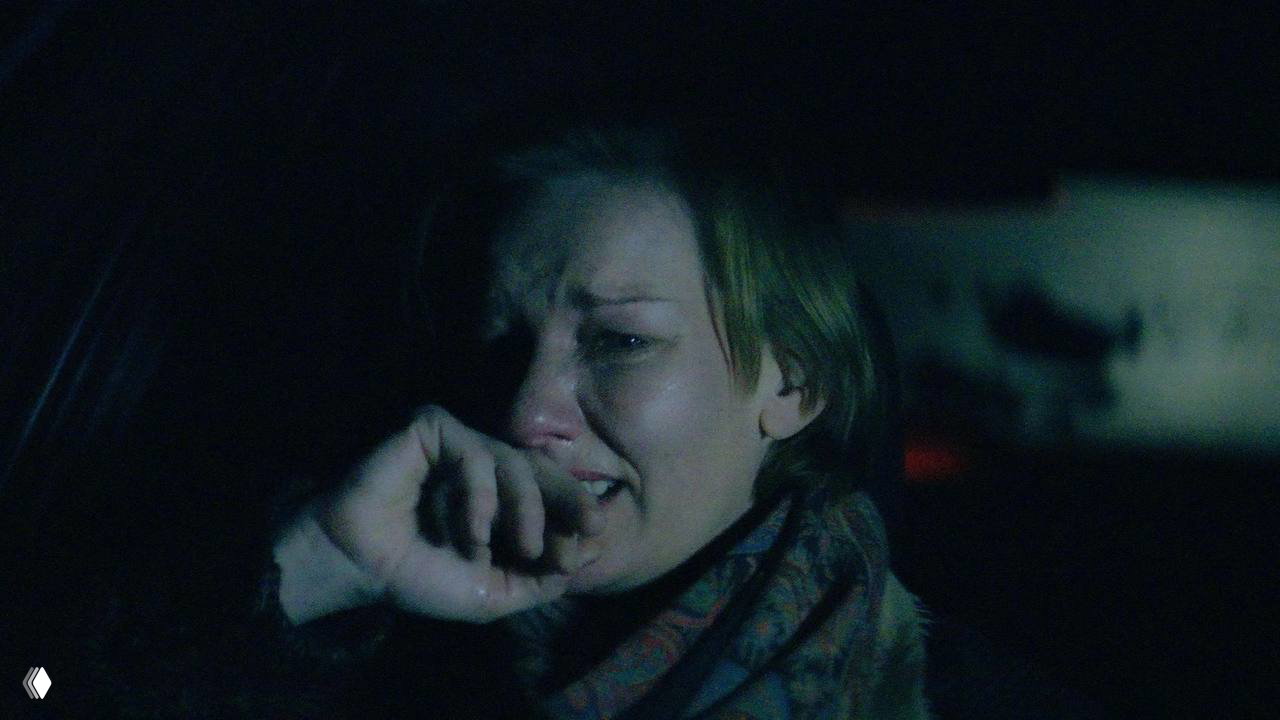 Ночной кадр: плачущая женщина в автомобиле, слёзы на лице и приглушённое освещение создают насыщенную эмоциональную атмосферу сцены.