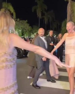 Две женщины в элегантных вечерних нарядах на красной дорожке кинофестиваля в Санта-Барбаре; рядом охранники и зрители.