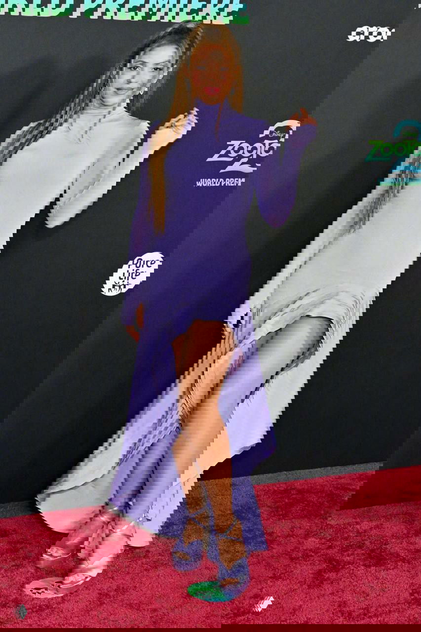 Шакира в обтягивающем лавандовом платье с высоким разрезом позирует на красной дорожке, образ завершён босоножками и длинными распущенными волосами.