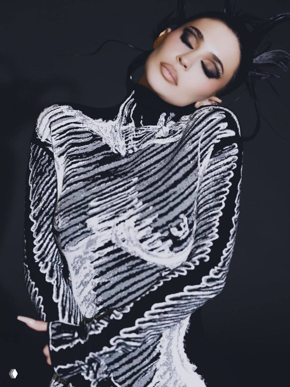 Крупный план: женщина в тёмном облегающем платье с графичным белым рисунком, глаза закрыты, драматичный макияж и причёска.