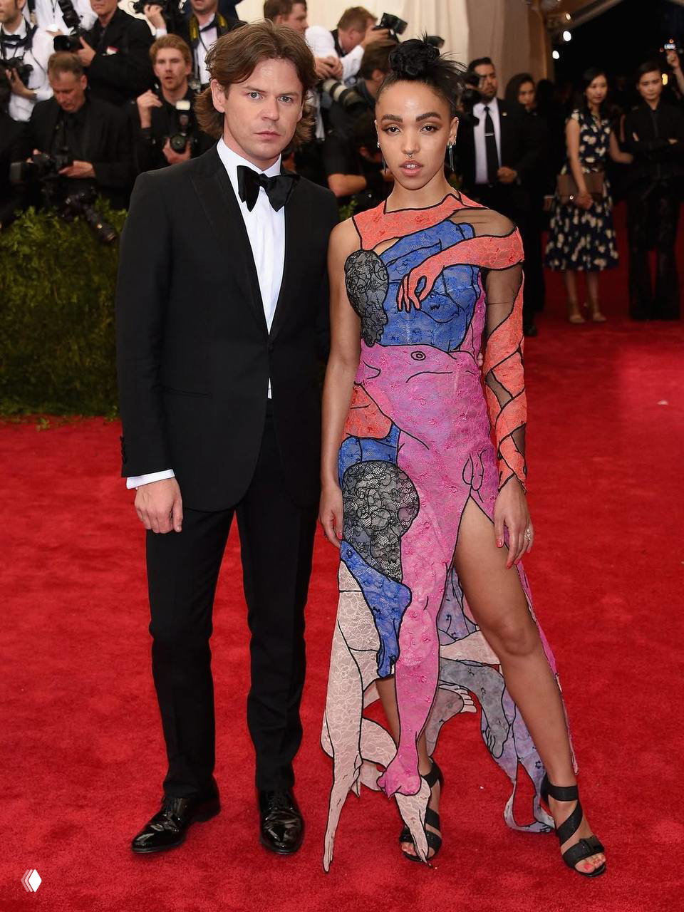 Кристофер Кейн и девушка на красной дорожке: он в смокинге, она в разноцветном абстрактном платье; на заднем плане — папарацци и гости.