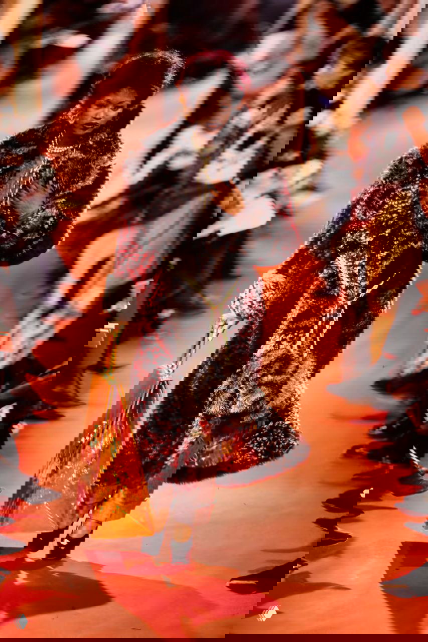 Модель в роскошном многослойном платье и широкой драпировке идёт по подиуму Vivienne Westwood осень 1993, букет в руках.