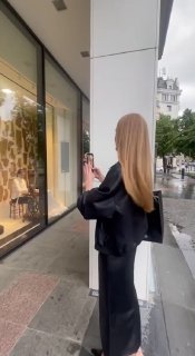 Посетительница фотографирует витрину 12 STOREEZ: женщина в чёрном у входа, отражение улицы и детали оформления фасада магазина в дождливый день