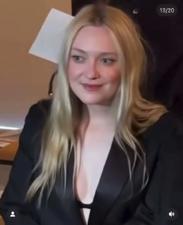 Крупный план женщины с распущенными волосами и глубоким вырезом в тёмном жакете на фоне посадочных мест — атмосфера модного мероприятия и backstage.