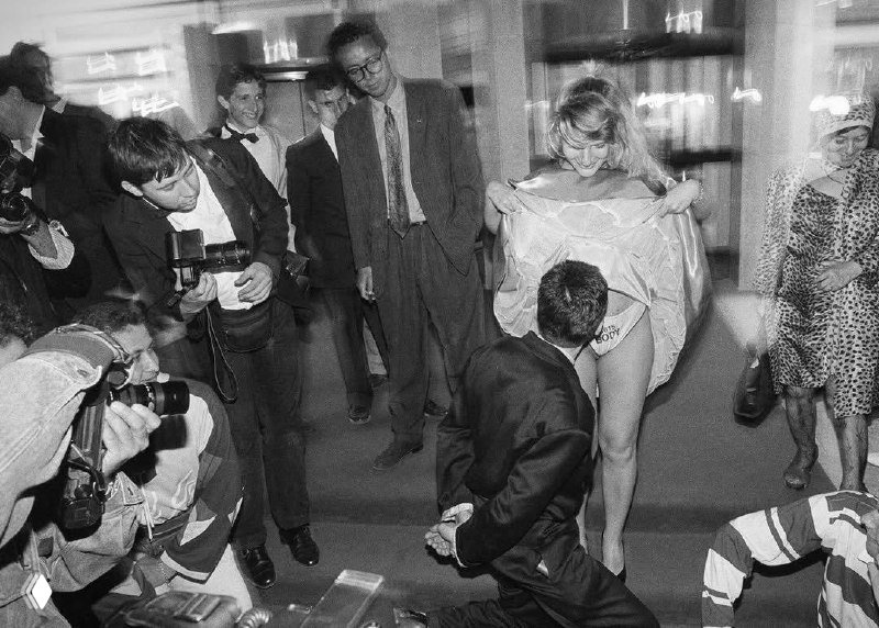 Черно-белый снимок 1980‑х: момент с моделями и папарацци, кадр передает энергетику вечернего события и стремление камер к сцене.
