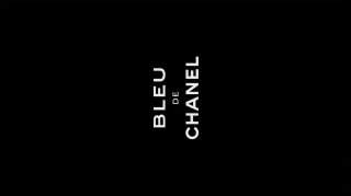 Стиллизованный кадр из ролика Bleu de Chanel: тёмный фон с вертикальной белой надписью «BLEU DE CHANEL», постерная эстетика рекламного короткометражного фильма.