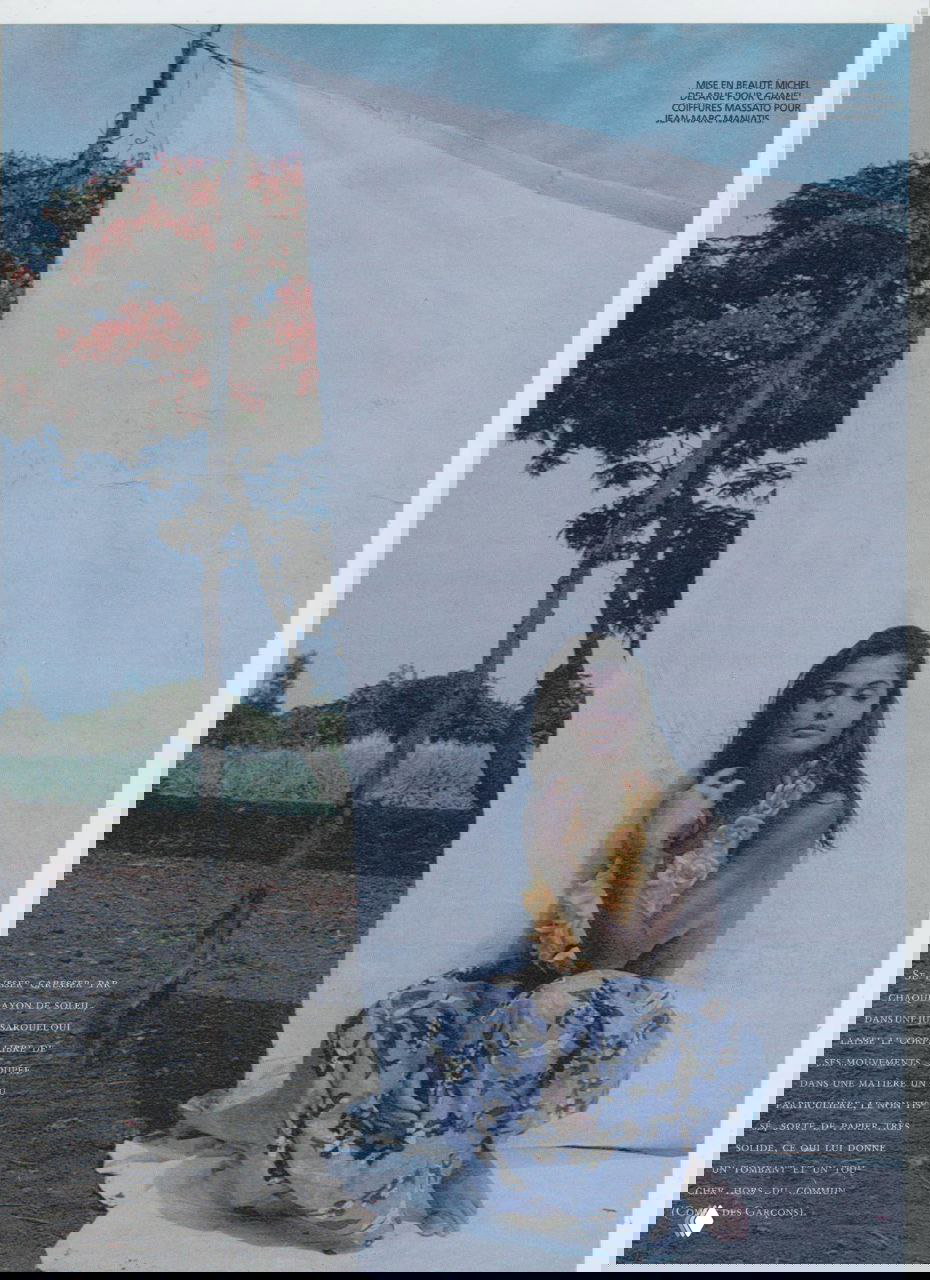 Модель сидит перед белым полотнищем на фоне тропического пейзажа; приглушённые тона и атмосфера ретро-фотосъёмки 1992 года.