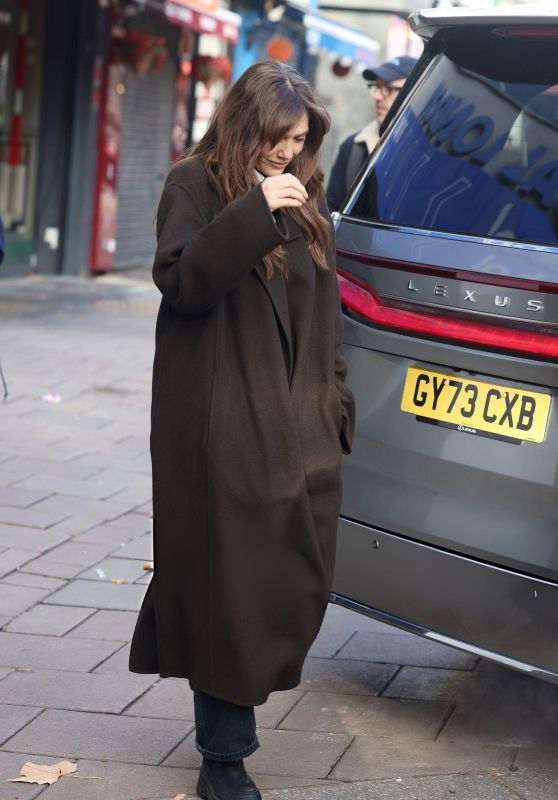 Уличный кадр: короткое тёмное пальто и широкие брюки в деловом стиле, городской тротуар и почтовый ящик позади.