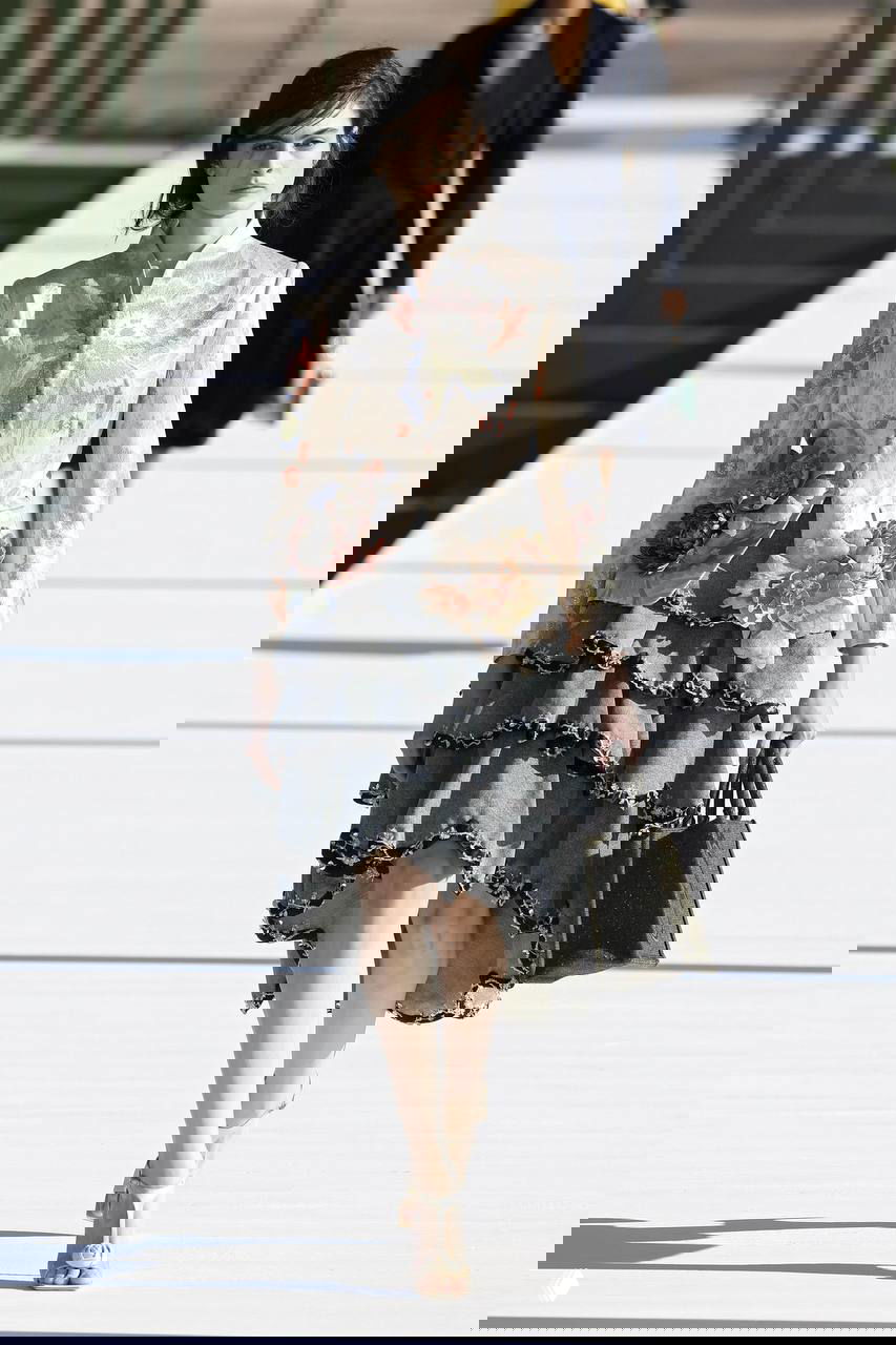 Модель в жакете с текстурными цветочными аппликациями и многоярусной юбкой, украшения и сумка дополняют образ, отсылающий к ботанической теме показа.