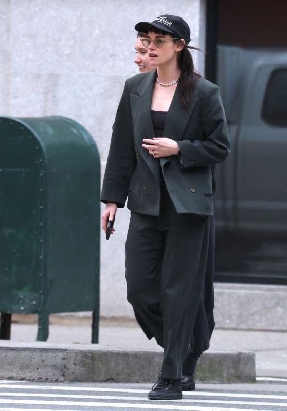 Аэропортный снимок: длинный кожаный плащ с меховыми элементами, капюшон и тёплая обувь, интерьер зала вылета на заднем плане.