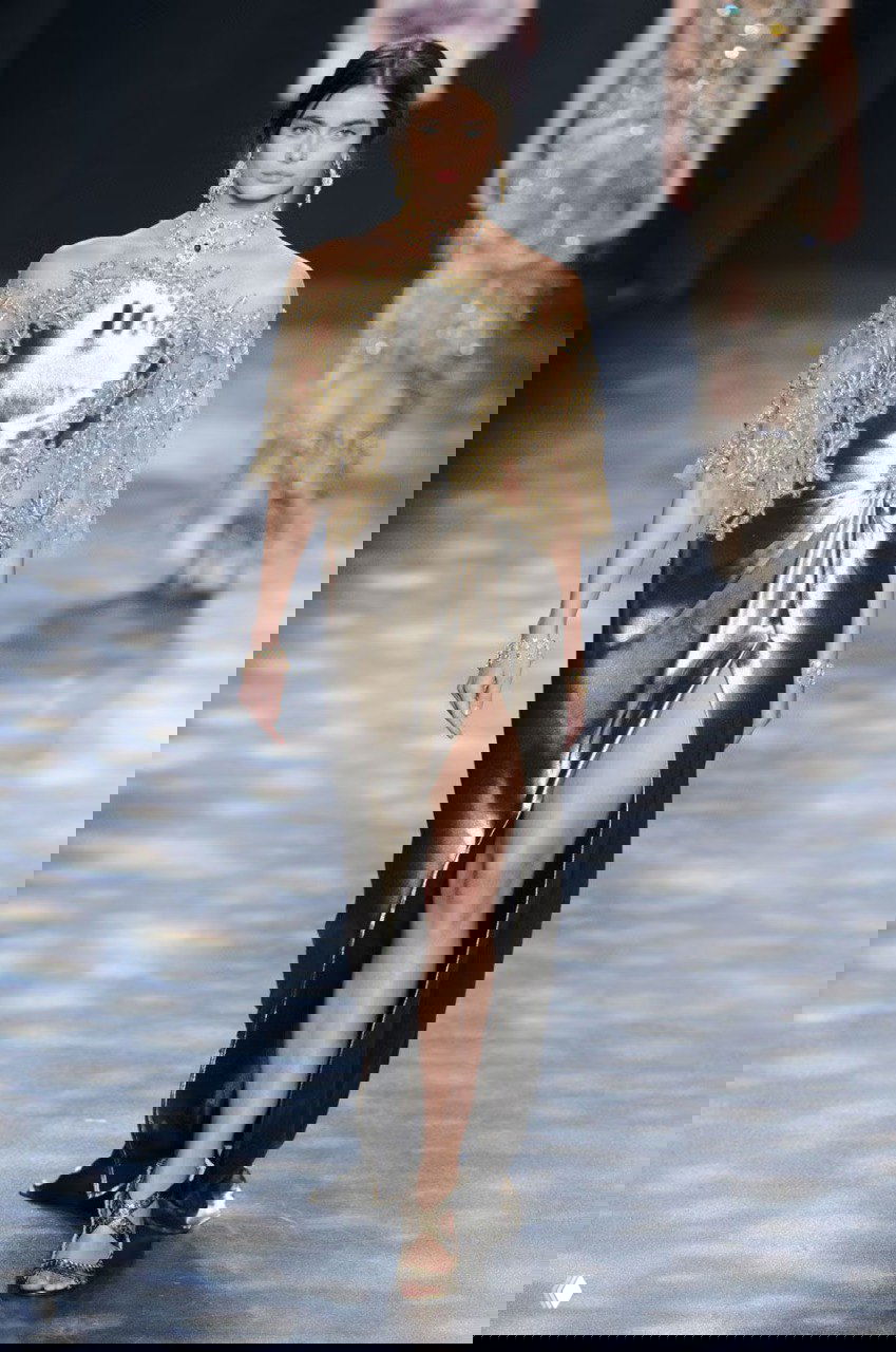 Элегантное металлически‑золотое платье Marchesa с высоким разрезом и вышивкой золотыми элементами — вечерний образ с глянцевым блеском.